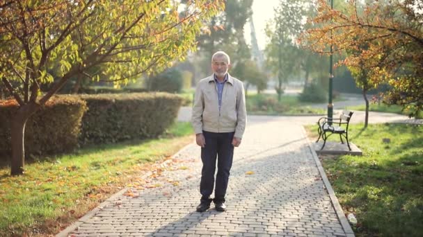 Uomo anziano in giacca. Vecchio barbuto che cammina nel parco autunnale — Video Stock