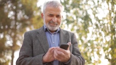 Dışarıda akıllı telefon kullanan beyaz sakallı ihtiyara yaklaş.