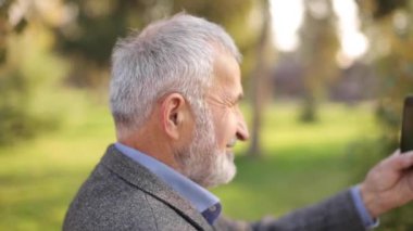Dışarıda telefon kullanan yaşlı bir adamın maketi. Yeşil ekran. Telefona zarar verecek mesafede bir adamın arka görüntüsü. Dedem akıllı telefondan video çekiyor.