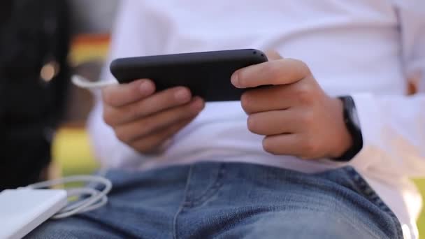 Adolescente en camisa blanca usar powerbank para cargar su otside teléfono inteligente. Batería baja en smartphone — Vídeo de stock