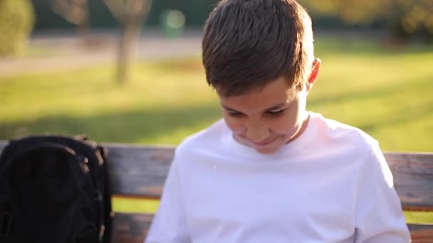 Хлопчик-підліток у білій сорочці дивиться в смартфон . — стокове відео