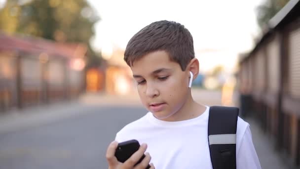 Adolescente chico poner en el bolsillo auriculares inalámbricos y teléfono — Vídeos de Stock