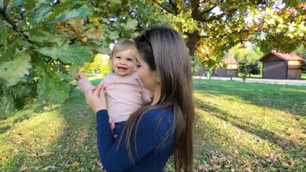 Mamá e hija juntas en otoño. Hermoso bebé de diez meses en las manos de las madres — Vídeo de stock