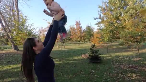 Anne ve kızı sonbaharda bir araya gelirler. Güzel on aylık bebek annesinin ellerinde. — Stok video