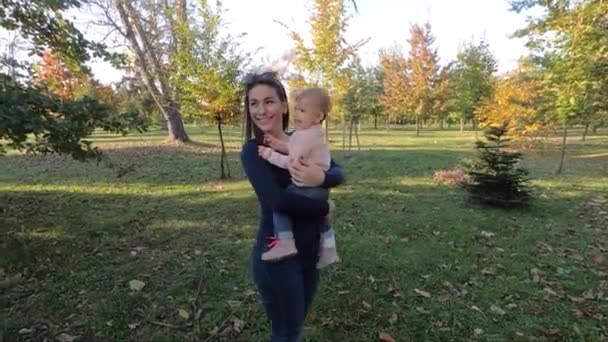 Anya és lánya együtt ősszel. Gyönyörű tíz hónapos baba az anyák kezén. — Stock videók