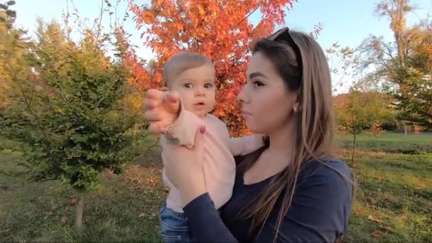 Matka se svou malou holčičkou stojí před červeným stromem. Podzimní park — Stock video