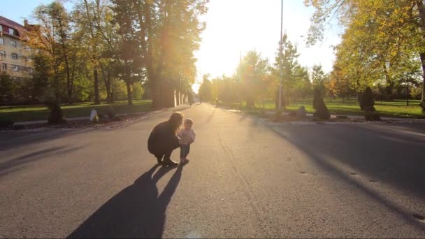 Menina adorável estudando para andar no parque com a mãe e o pai. Bonito andar de bebê de dez meses. Menina feliz bonita. Humor de outono — Vídeo de Stock