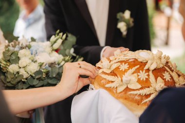 Damat ve gelin bir ekmek alın. Erkeklerin elinde bir buket çiçek. Beyaz ve mavi çiçekli güzel bir düğün buketi