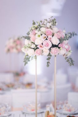 Düğün kutlaması için dekore edilmiş bir masa. Bir sürü penceresi olan parlak bir restoran. Masada çiçekler.