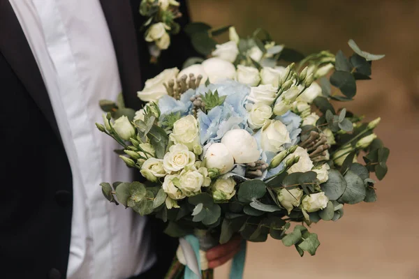 Blumenstrauß in Männerhand. schöner Hochzeitsstrauß mit weißen und blauen Blumen — Stockfoto