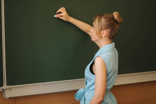 Professora a chiar a coisa na secretária da escola. Jovem professor — Fotografia de Stock