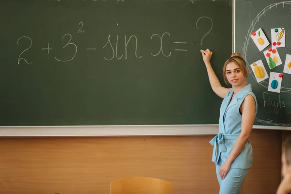 Profesora blanqueando las cosas en el escritorio de la escuela. Joven profesor — Foto de Stock