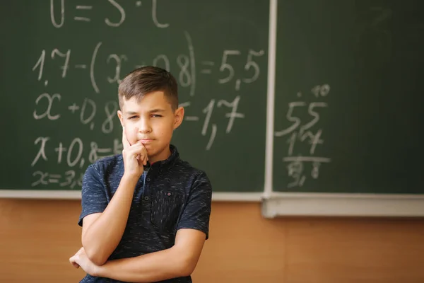 Το χαριτωμένο αγόρι στέκεται στο φόντο της τάξης του μαυροπίνακα. Εκπαίδευση. Δημοτικό σχολείο — Φωτογραφία Αρχείου
