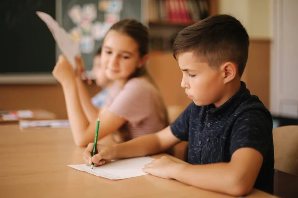 Sınıfta kalem ve defter yazan bir grup okul çocuğu. eğitim, ilkokul, öğrenme ve insan kavramı — Stok fotoğraf