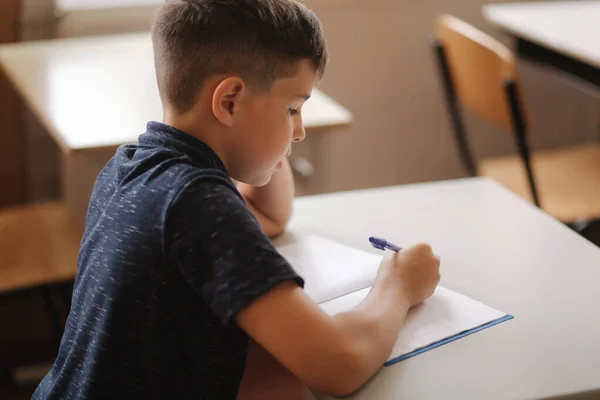 Boy and girl sitting at desk and writing a text — Stock Photo, Image