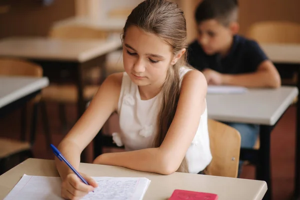 Junge und Mädchen sitzen am Schreibtisch und schreiben einen Text — Stockfoto