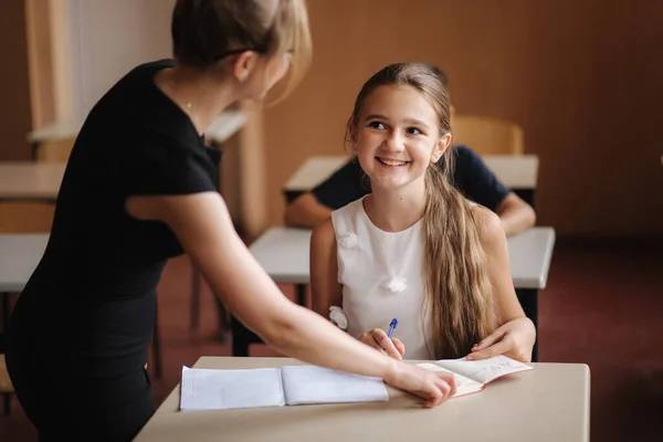 Profesor ayudando a los niños de la escuela a escribir prueba en clase. educación, escuela primaria, aprendizaje y concepto de personas — Foto de Stock