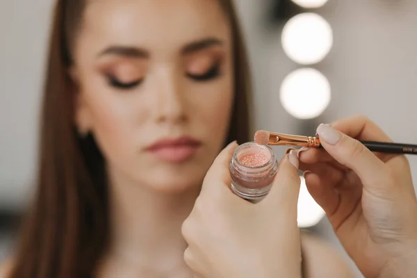 Makeup artysta stosuje cień do powiek, idealny makijaż wieczorem. Piękna ruda dziewczyna z idealną skórą i piegami — Zdjęcie stockowe