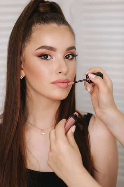 Ručně nalíčená umělkyně drží rtěnku a make-up. Krásný úsměv. Pozadí bílé sklopné obrazovky — Stock fotografie