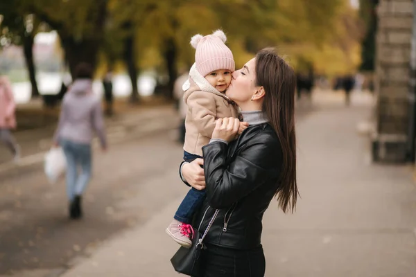 Adorable little girl on mothers hand in the park. Mom with daughter walk outside. Happy family in golden autumn — Stock Photo, Image