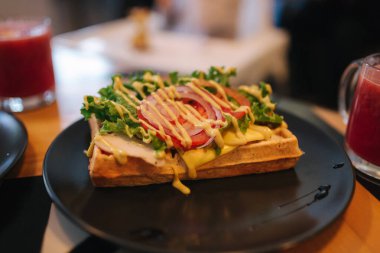 Pastırmalı gözleme sandviç ve siyah tabakta frech salatası. Ahşap masanın arka planı