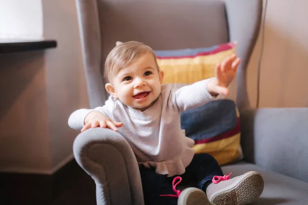 Linda niña sentada en un sillón grande y sonrisa — Foto de Stock