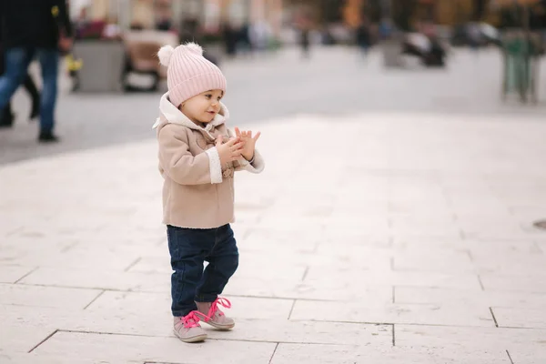 Gelukkige baby meisje wandelen in de stad in de herfst tijd. Leuke baby in bruine jas en jeans — Stockfoto