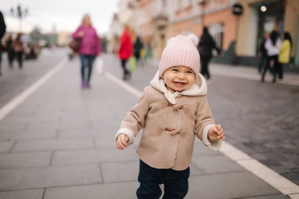 Portret van een klein meisje met een lachende jas en hoed. Schattige baby buiten — Stockfoto