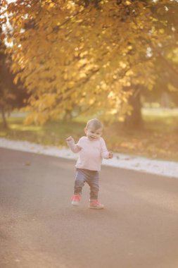 Sevimli küçük kız ekim ayında kilisede yürüyor. On aylık tatlı bebek yürüyüşü. Güzel, mutlu bir kız. Sonbahar havası