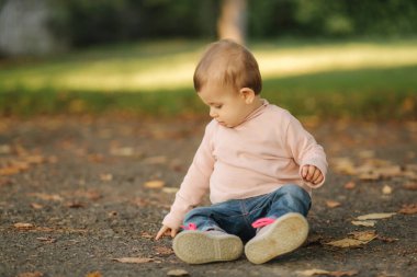Gülümseyen güzel küçük kıza yakın dur. Sonbahar parkında mutlu bir kız bebek. On aylık bebek gülümsemesi