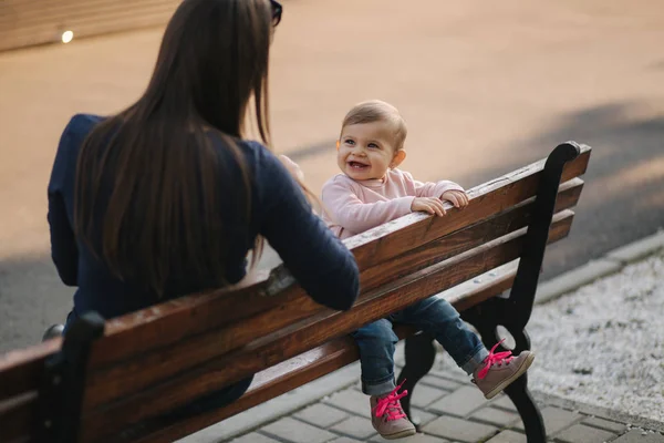 Kislány eszik a parkban, anya gyümölcsöt ad a babának. Anya és lánya ülnek a padon. — Stock Fotó