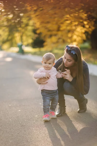 Lycklig liten flicka gå med mamma på hösten i parken — Stockfoto