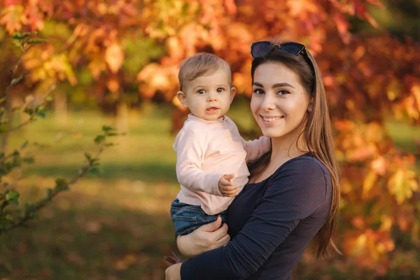 Matka se svou malou holčičkou stojí před červeným stromem. Podzimní park — Stock fotografie