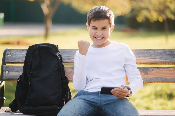 Teenage boy gioca online sul suo smartphone nel parco dopo le lezioni a scuola — Foto Stock