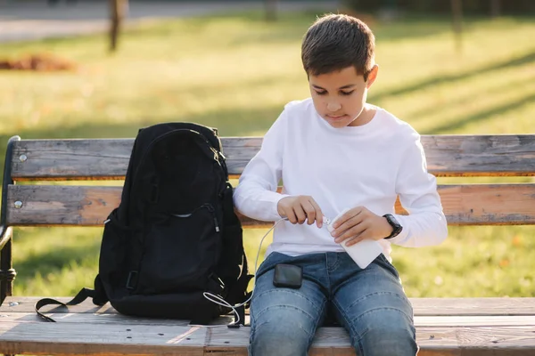 Tienerjongen in wit shirt gebruiken powerbank voor het opladen van zijn smartphone otside. Geen batterij op de smartphone — Stockfoto