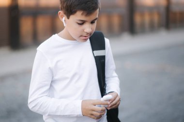 Genç çocuk müzik dinlemek için kablosuz kulaklık kullanıyor.