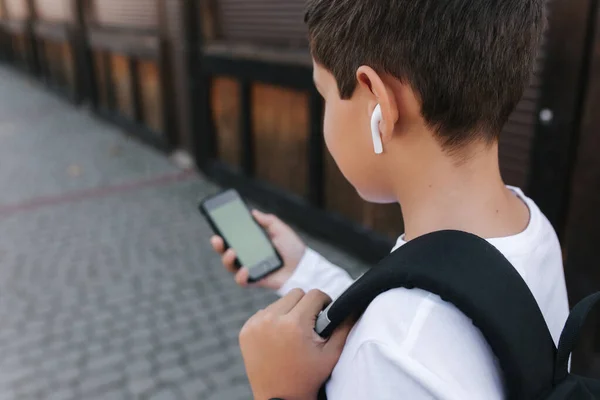 Vysmívat se puberťákovi s bezdrátovými sluchátky použít telefon otside. Zelená obrazovka — Stock fotografie