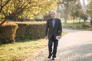 Yakışıklı son sınıf öğrencisi elinde gazeteyle parkta dolaşıyor. Sabahın erken saatlerinde parkta yürürken sakalını sakalına takmış.