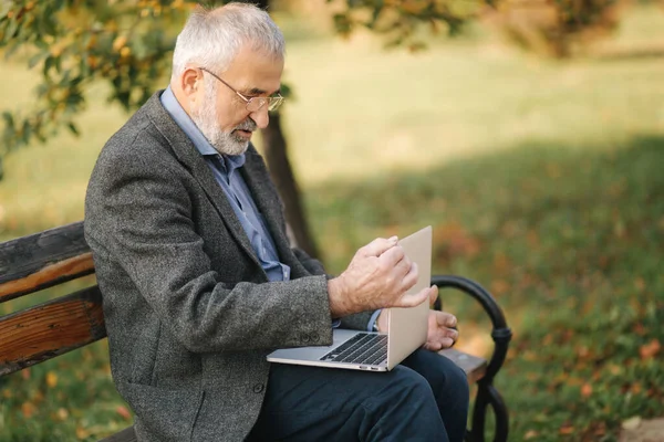 Farfar stänga laptop efter arbete i parken — Stockfoto