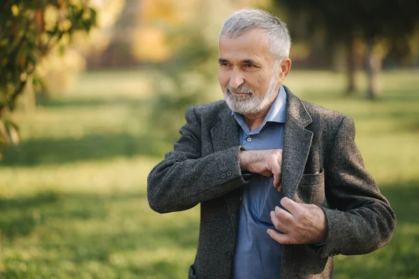 Handsome bearded old man take a smartphone from the jacket