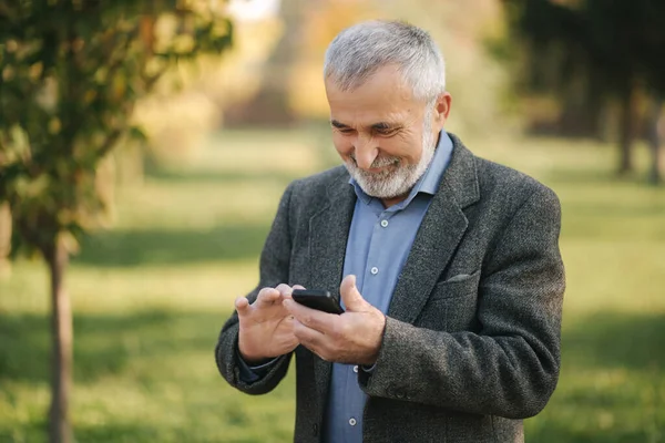 Närbild av gammal man med vitt skägg med hjälp av smartphone utanför — Stockfoto