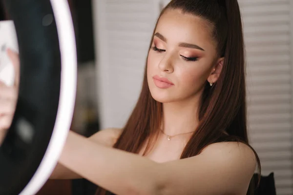 Jong aantrekkelijk model Maak een selfie na make-up in Beauty Studio. Ze gebruikt een ring LAPM voor foto. Achtergrond van wit vouwscherm — Stockfoto