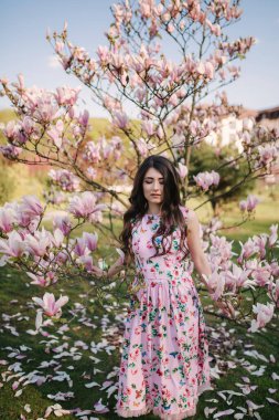 Sevimli kız güzel pembe manolya ağacı dışında standı. Muhteşem bayan