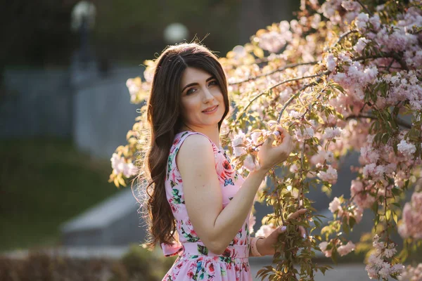 Elegantní žena v krásných šatech u růžového stromu v parku — Stock fotografie