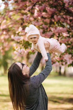 Mutlu genç anne elinde bebek kız tutan ve sevgi ile ona bakarak Yan görünümü