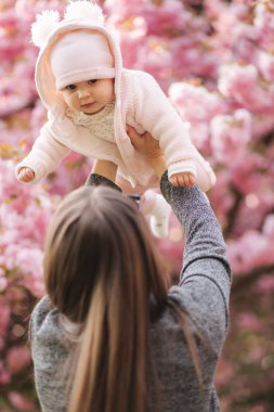 Mutlu genç anne elinde bebek kız tutan ve sevgi ile ona bakarak Yan görünümü