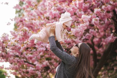 Mutlu genç anne elinde bebek kız tutan ve sevgi ile ona bakarak Yan görünümü