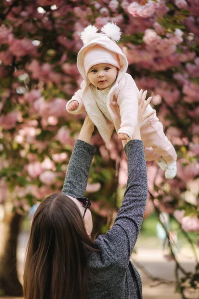 Πλευρική όψη της ευτυχης νεαρής μητέρας κρατώντας το κοριτσάκι στα χέρια της και κοιτάζοντας την με αγάπη — Φωτογραφία Αρχείου