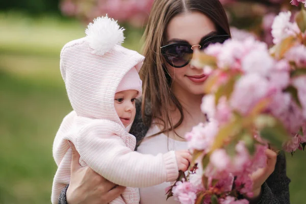 Mor med liten dotter i parken promenad nära Sakura Tree — Stockfoto