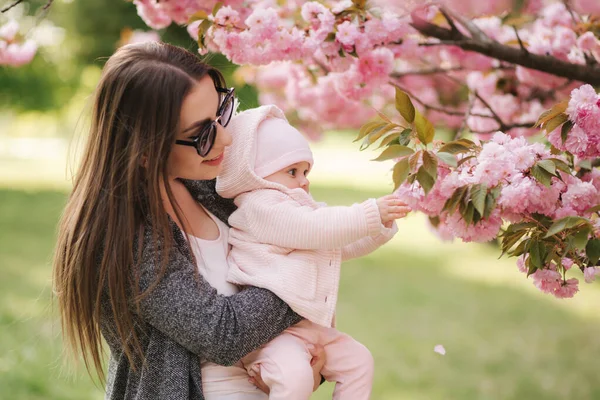 Mor visar granar tid till dottern Pink Tree. Happy baby Hold gren av Sakura — Stockfoto